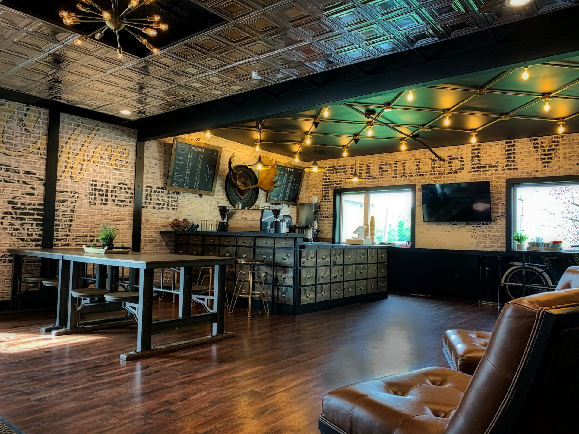 Restored historic main-street interior with stamped tin ceiling, exposed brick, and a coffee bar